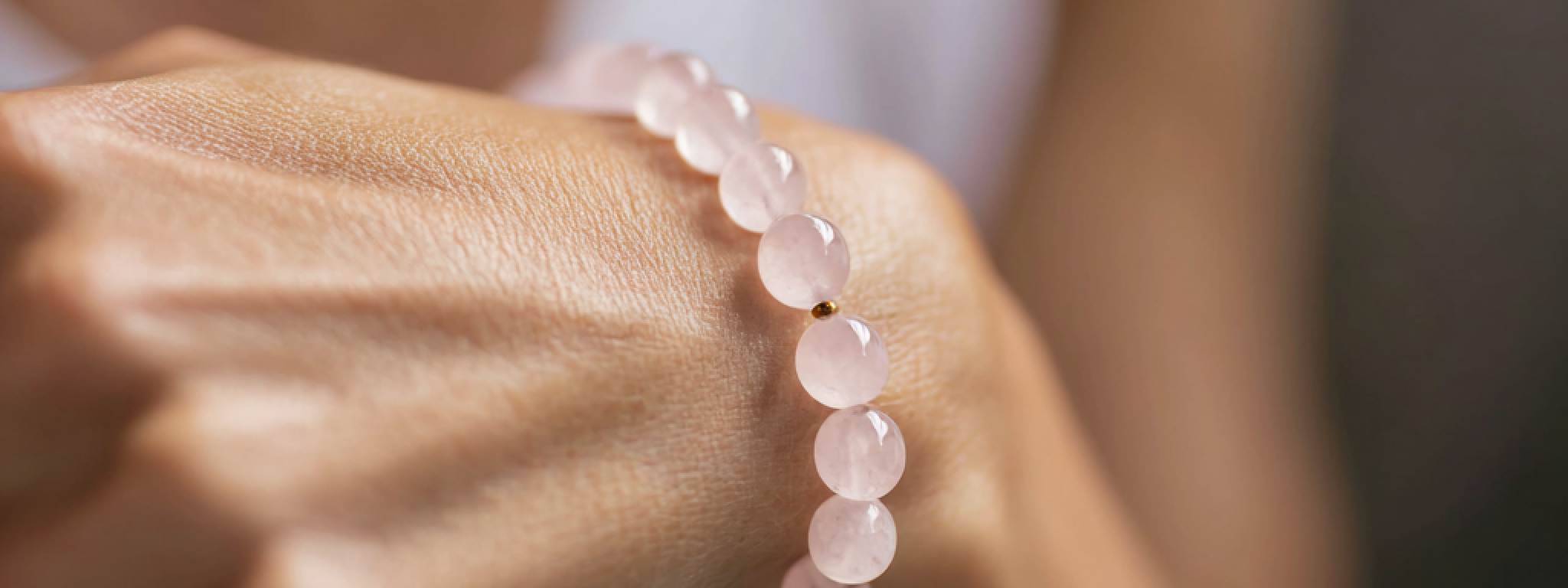 Bracelet en perles de quartz rose porté au poignet, symbole d’amour et de sérénité, bijou en pierre naturelle aux vertus apaisantes.